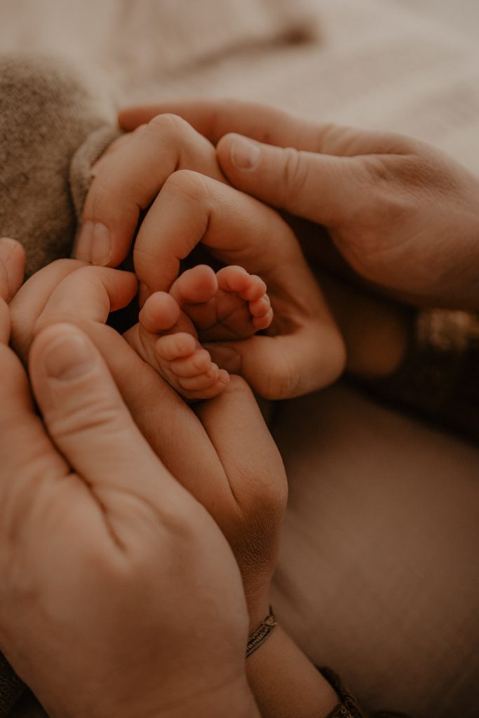 Mains posées autour des petits pieds de bébé
