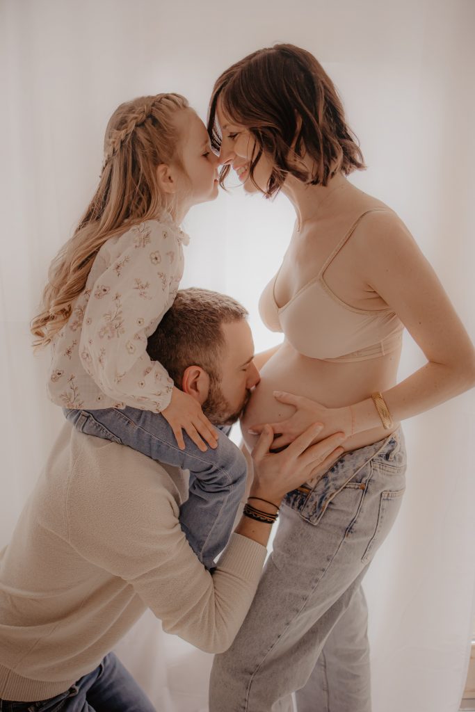 Petite fille sur les épaules de son papa pour faire un bisou à maman